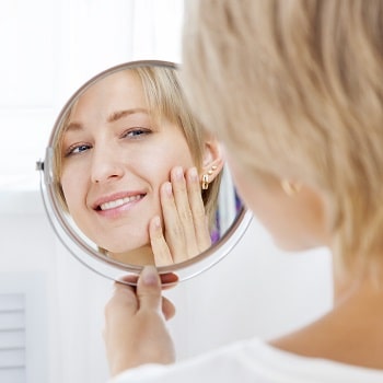 Woman looking at her dental implants in the mirror